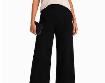 May include: A cream-coloured sleeveless top and black, wide-leg cropped trousers. The outfit is accessorised with a black clutch and black heeled sandals. A gold necklace adds a touch of elegance to the ensemble.