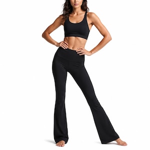Könnte beinhalten: Ein einfarbig schwarzes Sportset bestehend aus einem Sport-BH mit Rundhalsausschnitt und Ringerrücken sowie einer hoch taillierten, ausgestellten Leggings. Die Leggings ist an Hüfte und Oberschenkeln eng geschnitten und läuft unten weit aus.