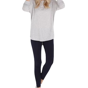 May include: A gray long-sleeved shirt with a relaxed fit and a pair of dark blue leggings.