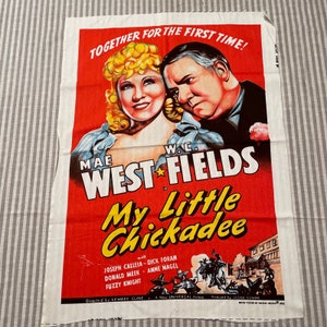 May include: A vintage movie poster for the film "My Little Chickadee" starring Mae West and W.C. Fields. The poster features a red background with a yellow and black title and the actors' names in white. The poster also includes a scene from the film with the actors in costume.