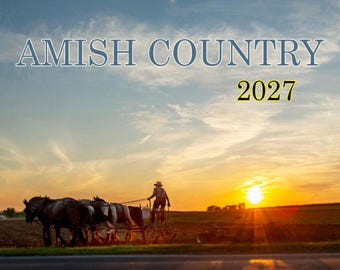 May include: A calendar cover titled AMISH COUNTRY 2027 featuring a silhouette of a person driving a horse-drawn plow in a field during a bright orange sunset. The sky is filled with wispy clouds above a dark horizon line and a paved road.