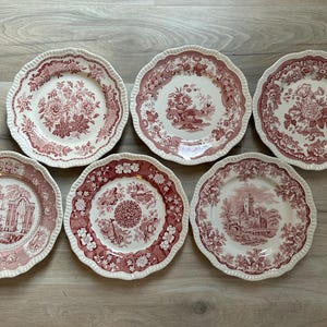 May include: Set of six vintage pink and white floral patterned dinner plates. The plates have a scalloped edge and a delicate floral design.