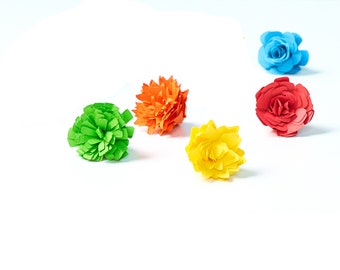 May include: Five paper flowers in different colors: green, orange, red, yellow, and blue. The flowers are arranged on a white background.