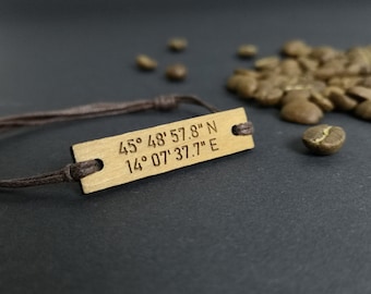 May include: A brown leather cord bracelet with a wooden tag engraved with the coordinates "45° 48' 57.8" N 14° 07' 37.7" E".