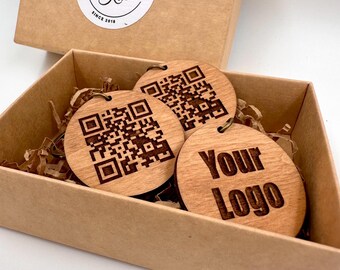 May include: Three round wooden tags in a brown box. Two tags have a black and white QR code design. The third tag has the text "Your Logo" engraved on it.