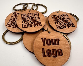 May include: A set of wooden keychains with a laser-engraved QR code and the text "Your Logo". The keychains are brown and have a brass ring.