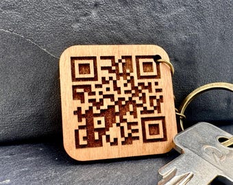 May include: A wooden keychain with a laser-engraved QR code. The keychain is attached to a silver key ring.