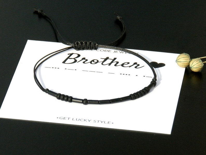 Pode incluir: Pulseira preta de contas com um cord&atilde;o preto e um fecho de n&oacute; deslizante. A pulseira &eacute; exibida em um cart&atilde;o branco com a palavra "Brother" escrita em it&aacute;lico preto.