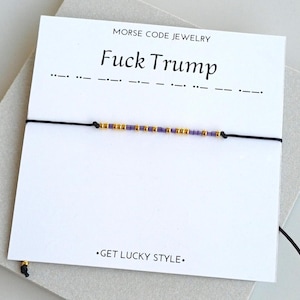 May include: A white ceramic mug with a black handle and the text "But First, Coffee" in a black, handwritten-style font. The mug is on a white surface.