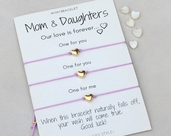 May include: Three purple string bracelets with gold heart charms. The card reads "Mom & Daughters Our love is forever... One for you One for you One for me When this bracelet naturally falls off, your wish will come true. Good luck!"