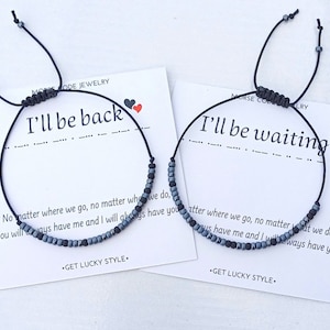 Peut inclure: Deux bracelets en cordon noir avec des perles grises, chacun avec une carte qui dit "Je reviendrai" et "J'attendrai" en code Morse. Les cartes comprennent également le texte "Peu importe où nous allons, peu importe ce que nous faisons, tu me auras toujours et je t'aurai toujours."