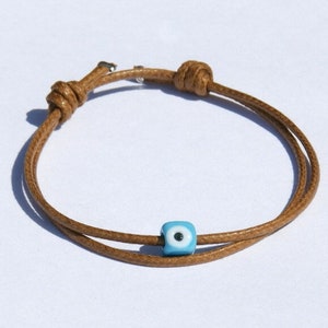 May include: A brown leather cord bracelet with a blue evil eye bead charm.