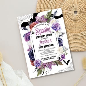 May include: A white invitation card with a purple, black, and white floral design. The text on the card reads "You're invited to our Spooky Birthday Party Celebrating Jessica's 10th Birthday!"  The invitation includes the date, time, and location of the party.