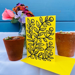 Tarjeta de felicitación floral: diseño original en linograbado con líneas fluidas sobre cartulina amarilla vibrante.