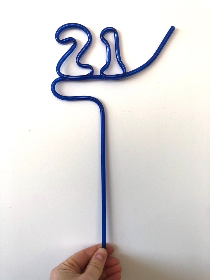 May include: A blue plastic drinking straw bent into the shape of the number 21.