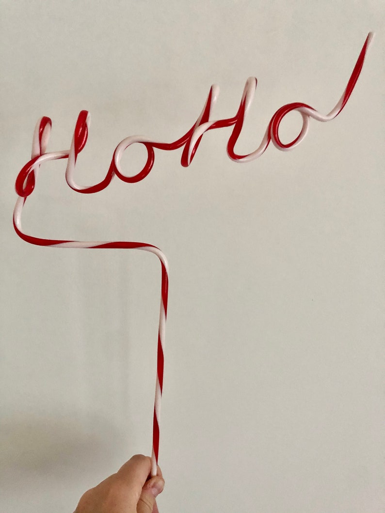 May include: A red and white striped plastic straw bent into the word "hello".