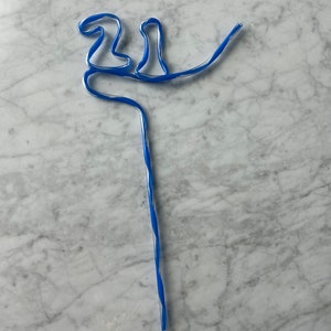 May include: A blue and white striped drinking straw bent into the shape of a bird.