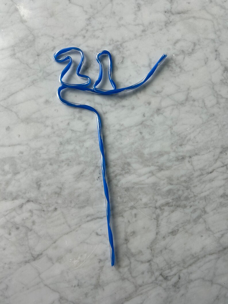 May include: A blue and white striped drinking straw bent into the shape of a bird.