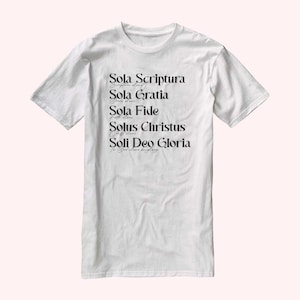 Puede incluir: Camiseta blanca con texto negro que dice "Sola Scriptura", "Sola Gratia", "Sola Fide", "Solus Christus" y "Soli Deo Gloria".