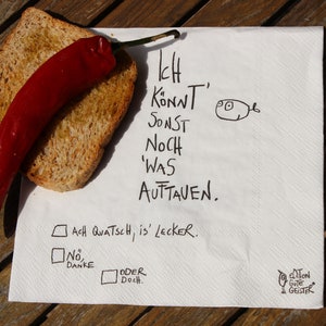 May include: A white napkin with black handwritten text that reads "Ich Konnt' Sonst Noch 'Was Auftauen. Ach Quatsch, is' Lecker. No Danke Oder Doch." There is a red chili pepper and a piece of toasted bread on the napkin.