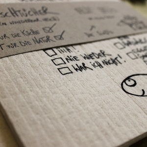 May include: A close-up of a brown paper package with the text "3 WiscHTUCHER (WERDEN WHitech GUT FUR DIE KICHE✓ GUT F&Uuml;R DIE NATURAㄧˋˋˋ" written on it. The package is folded over and has a white check mark next to the text "GUT FUR DIE KICHE". The package is also labeled with the text "NIE WIEDER" and "WAR ICH NICHT!" in black marker.