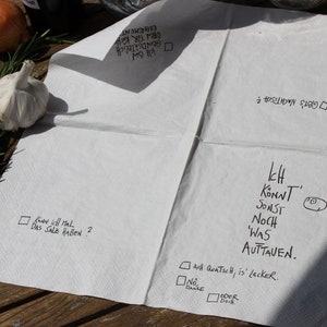 May include: A white paper napkin with handwritten text in black ink. The text reads: "Know soll mal das Salz haben?" and "Ich Konnt Sonst Noch 'Was Auttaven." There are also checkboxes with the text "All Quatsch, is' lecker." and "No, Danke."