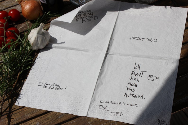 May include: A white paper napkin with handwritten text in black ink. The text reads: "Know soll mal das Salz haben?" and "Ich Konnt Sonst Noch 'Was Auttaven." There are also checkboxes with the text "All Quatsch, is' lecker." and "No, Danke."