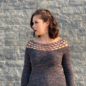 May include: A long-sleeved, black and purple sweater with a crocheted neckline. The sweater has a fitted silhouette and is made of a soft, textured yarn.
