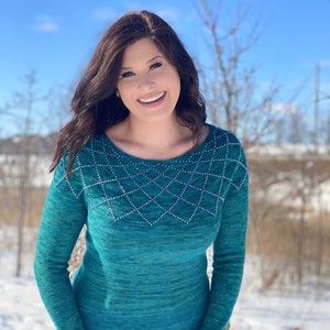 Può includere: Un maglione blu turchese con un motivo geometrico di perline argentate sul collo e sui polsini. Il maglione è lavorato a maglia e ha una vestibilità comoda.