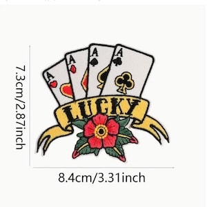 以下が含まれることがあります： 4 つのエースのトランプカードと赤い花、そして黒い文字で「LUCKY」と書かれた黄色のバナーが描かれた刺繍のアイロン接着パッチ。パッチの幅は 8.4 cm、高さは 7.3 cm です。