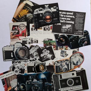 Può includere: Un collage di pubblicità e immagini di prodotti di macchine fotografiche vintage. Il collage presenta vari marchi di macchine fotografiche, tra cui Minolta, Pentax, Canon e Polaroid. Le immagini sono stampate su carta e hanno un'estetica vintage usurata.