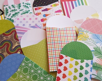 May include: A collection of colorful paper envelopes with various patterns, including stripes, stars, hearts, and tropical leaves. The envelopes are all folded in half and have a rounded flap.