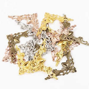 May include: A collection of ornate metal corner brackets in gold, silver, and bronze finishes. The brackets have a decorative, intricate design with a pointed tip.