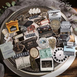 Può includere: Una collezione di adesivi in stile vintage con macchine da scrivere, cassette postali, lampade e altre immagini nostalgiche. Gli adesivi sono disposti su un vassoio argentato con sfondo nero. Gli adesivi hanno parole come "Magia", "Felice" e "Ricordi" stampate su di essi.