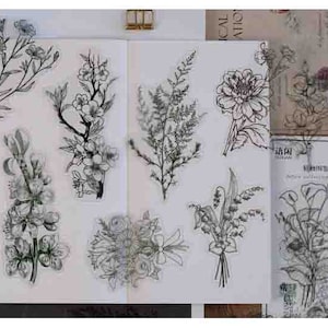 May include: A sheet of clear stamps featuring black line drawings of various flowers and plants. The stamps include a bouquet of lilies, a single dahlia, a fern, a branch of blossoms, and a bouquet of calla lilies.