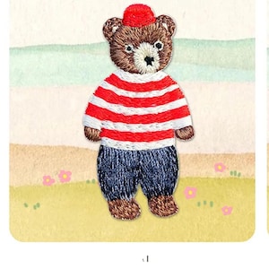 May include: Embroidered iron-on patch of a brown bear wearing a red and white striped shirt, blue jeans, and a red hat. The patch measures 51 mm by 26 mm.