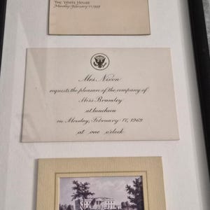 May include: Framed White House luncheon menu and invitation from 1969. The menu includes Celery Consommé, Chicken and Mushroom Crêpes, and Fresh Fruits au Kirsch. The invitation is addressed to Miss Brumley. A small print of the White House is also included.