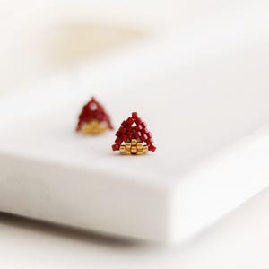 May include: A pair of small triangle-shaped earrings made with red and gold beads.
