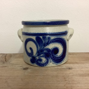 May include: A white ceramic crock with blue and white floral designs and two handles.