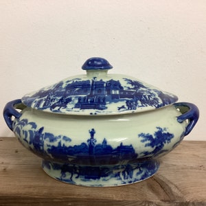Könnte beinhalten: Eine weiße Keramik-Servierplatte mit einem blauen und weißen Blumenmuster. Die Platte hat einen Deckel und zwei Griffe.