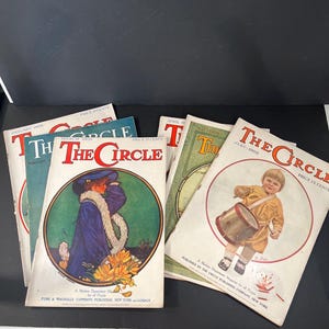 May include: A collection of vintage "The Circle" magazines. The covers feature illustrations of a child playing a drum, a woman in a blue coat, and other images. The magazines are from 1908 and have the price of 15 cents.