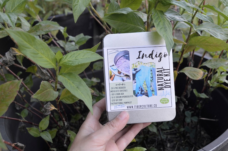 May include: A metal tin with a label that says "Indigo Natural Dye Kit" and includes a list of ingredients: 20 g Pre-Reduced Indigo Dye Crystals, 100 g Soda Ash, 50 g Sodium Hydrosulphite, 1 Step by Step Instructional Pamphlet, www.fiberculture.co. The tin is in the hand of a person.