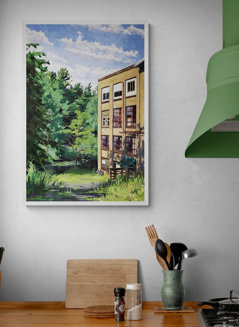May include: A framed painting of a yellow building with multiple windows, set against a backdrop of lush green trees and a blue sky with white clouds. The building appears to be an old factory or mill.
