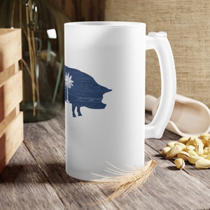 May include: White ceramic mug with a blue silhouette of a pig with a palm tree inside. The mug has a frosted finish.