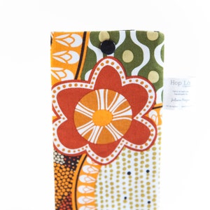 May include: A fabric case with a vibrant floral design in orange, white, and yellow. The case features a large, stylized flower and a button closure. The background is white.