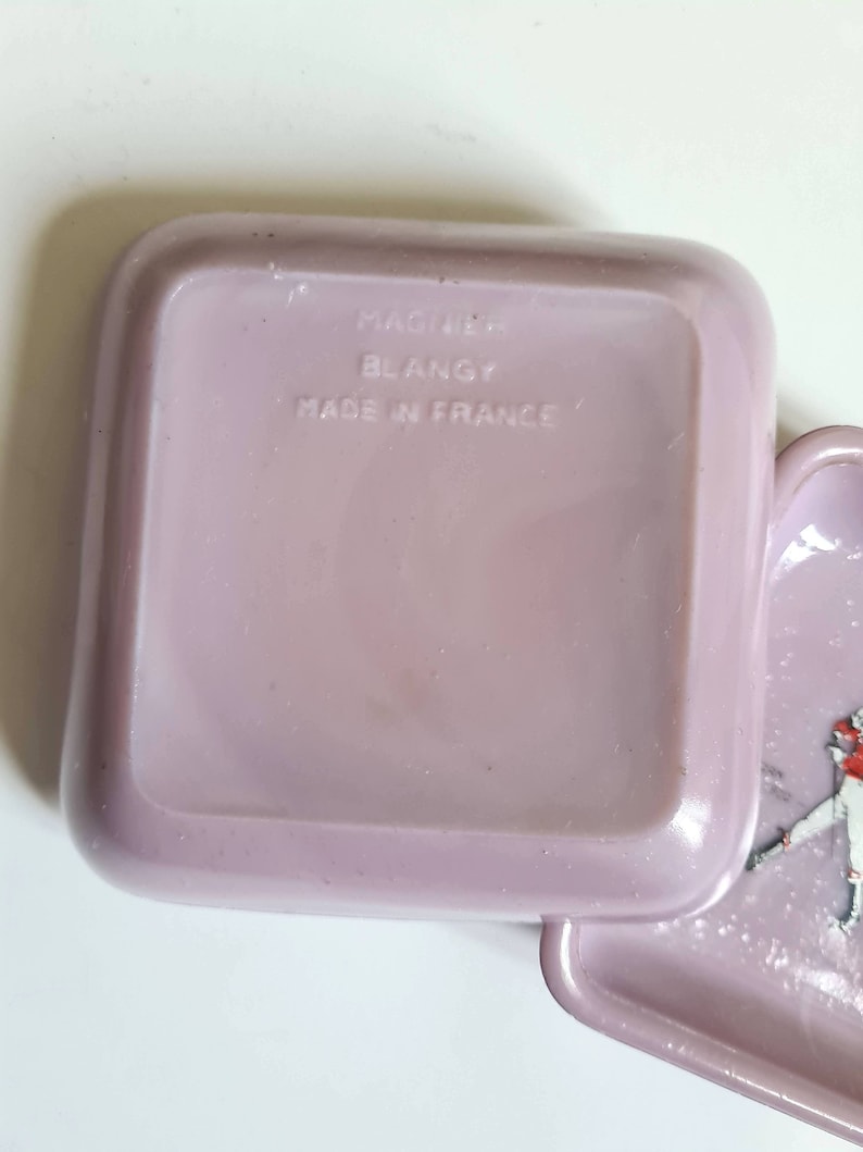 K&ouml;nnte beinhalten: Eine quadratische, violette Plastikbox mit abgerundeten Kanten. Die Box tr&auml;gt ein Etikett mit der Aufschrift "Made in France" und "Mastur Blangy".