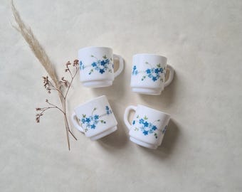 May include: Set of four white ceramic mugs with blue floral designs. The mugs have a simple, classic design and are perfect for everyday use.