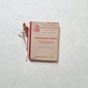 Peut inclure: Un livre rouge et blanc intitulé "Grammaire Latine" avec le texte "Methode Moderne d'Humanites Latines" et "Memento du Latiniste" sur la couverture.
