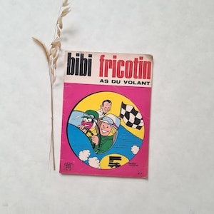 Peut inclure: Bande dessinée vintage "Bibi Fricotin AS DU VOLANT" avec une couverture rose et rouge. La couverture présente une illustration de bande dessinée de deux personnes dans une voiture de course, un drapeau à damier et le numéro 5. Une brindille d'herbe séchée est à côté de la bande dessinée.