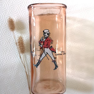Peut inclure: Un verre &agrave; boire en verre rose avec une image imprim&eacute;e d'un homme en veste rouge et pantalon blanc marchant avec une canne. Le texte "Still Going Strong" est imprim&eacute; sur le verre.